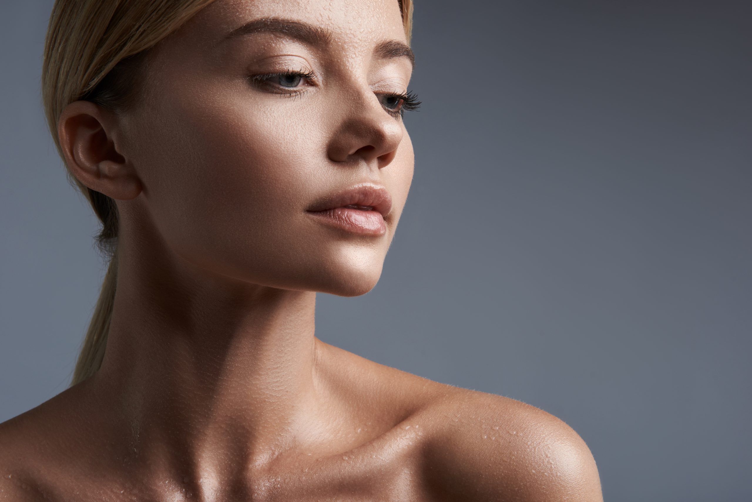 Sensual portrait of young woman sitting against the grey background